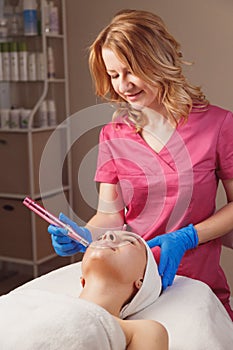 Professional cosmetology. Beautician is using dermapen on woman face skin. Skin beauty and health photo