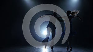 Professional couple of rumba dancers posing in smoky studio, silhouette