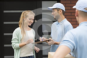 Professional couriers delivering package to smiling woman