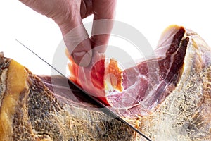 Professional cutter hand carving slices from a whole bone serrano jamon. Knife cutting a spanish serrano ham. Hands of a chef cutt