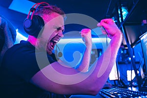 Professional cyber gamer playing online tournaments computer with headphones, Blurred Red and Blue background