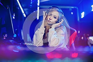 Professional cyber video gamer woman in studio room with personal computer armchair, neon color blur background