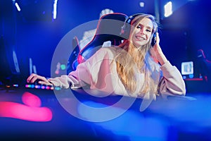 Professional cyber video gamer woman in studio room with personal computer armchair, neon color blur background