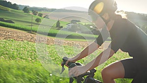 Professional cyclist riding bicycle at sunrise. Confident strong sportive female athlete cycling on bicycle at sunset. Sport recre