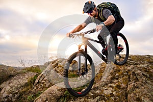 Professional Cyclist Riding Bike on the Autumn Rocky Trail at Sunset. Extreme Sport and Enduro Biking Concept.