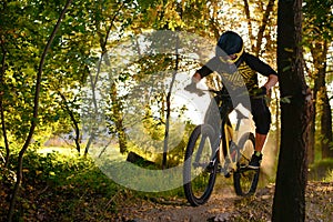 Professional Cyclist Riding the Mountain Bike on the Autumn Forest Trail. Extreme Sport and Enduro Cycling Concept.