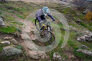 Professional Cyclist Riding Mountain Bike Down the Rocky Hill. Extreme Sport and Enduro Biking Concept.