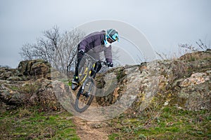 Professional Cyclist Riding Mountain Bike Down the Rocky Hill. Extreme Sport and Enduro Biking Concept.