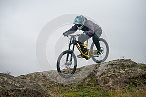 Professional Cyclist Riding Mountain Bike Down the Rocky Hill. Extreme Sport and Enduro Biking Concept.