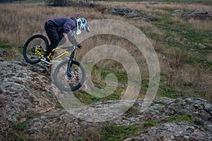 Professional Cyclist Riding Mountain Bike Down the Rocky Hill. Extreme Sport and Enduro Biking Concept.