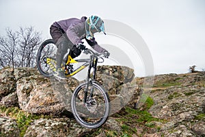 Professional Cyclist Riding Mountain Bike Down the Rocky Hill. Extreme Sport and Enduro Biking Concept.