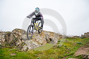 Professional Cyclist Riding Mountain Bike Down the Rocky Hill. Extreme Sport and Enduro Biking Concept.