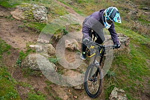 Professional Cyclist Riding Mountain Bike Down the Rocky Hill. Extreme Sport and Enduro Biking Concept.