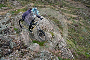 Professional Cyclist Riding Mountain Bike Down the Rocky Hill. Extreme Sport and Enduro Biking Concept.