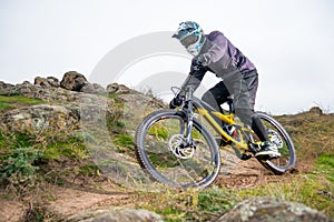 Professional Cyclist Riding Mountain Bike Down the Rocky Hill. Extreme Sport and Enduro Biking Concept.