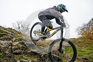 Professional Cyclist Riding Mountain Bike Down the Rocky Hill. Extreme Sport and Enduro Biking Concept.