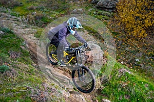 Professional Cyclist Riding Mountain Bike Down the Rocky Hill. Extreme Sport and Enduro Biking Concept.