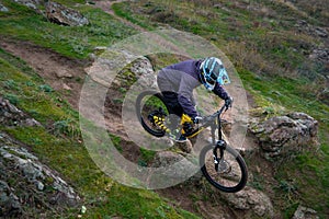 Professional Cyclist Riding Mountain Bike Down the Rocky Hill. Extreme Sport and Enduro Biking Concept.