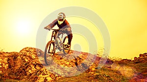 Professional Cyclist Riding Mountain Bike Down the Rocky Hill. Extreme Sport and Enduro Biking Concept.