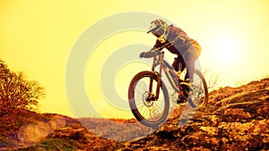 Professional Cyclist Riding Mountain Bike Down the Rocky Hill. Extreme Sport and Enduro Biking Concept.