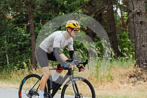 Professional cyclist in sports equipment rides in the park and trains outside the city