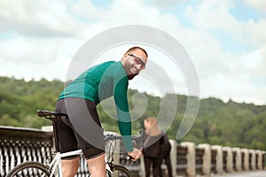 A professional cyclist in sportswear with glasses is preparing for a morning bike ride in a green city park. The concept