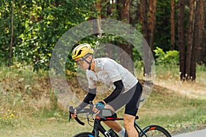 Professional cyclist trains on a bicycle outside the city in the woods, rides a bicycle with a serious face