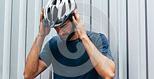 Professional cyclist wears the protective helmet and thinking about the route for triathlon outdoor. Male athlete preparing before