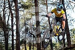 Professional Cyclist in Yellow T-shirt and Helmet Riding the Mountain Bike in Forest. Extreme Sport Concept.