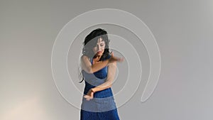 Professional dancer dancing flamenco in a blue dress against the background of a white wall. Spanish dance moves in slow