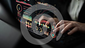 Professional Data Analyst Working with Modern Digital Graphs and Charts on Laptop in a Dark Office Environment