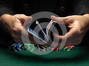 Professional dealer or croupier shuffles playing cards in a club at a green table with playing chips. The concept of a successful