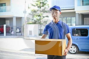 Professional delivery man holding the package for customer while standing in front of his van