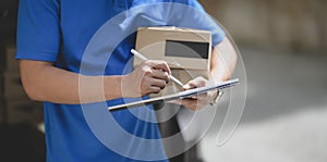 Professional delivery man working with parcel box while checking customer order on tablet