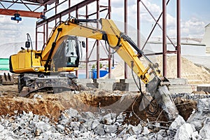 Professional demolition of reinforced concrete structures using industrial hydraulic hammer with excavator. Rods of metal fittings