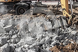 Professional demolition of reinforced concrete structures using industrial hydraulic hammer with excavator. Rods of metal fittings