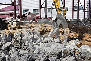 Professional demolition of reinforced concrete structures using industrial hydraulic hammer with excavator. Rods of metal fittings