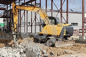 Professional demolition of reinforced concrete structures using industrial hydraulic hammer with excavator. Rods of metal fittings