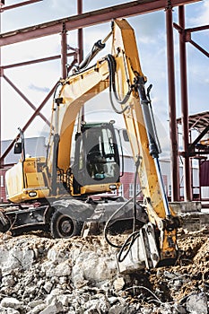 Professional demolition of reinforced concrete structures using industrial hydraulic hammer with excavator. Rods of metal fittings