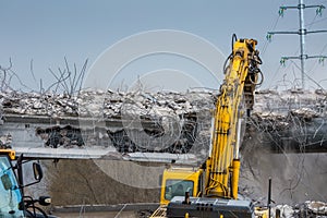 Professional demolition of reinforced concrete structures using industrial hydraulic hammer. Rods of metal fittings. Wreckage and