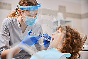 Professional dentist is giving anesthesia to a child