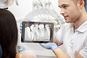 Professional dentist showing his client x-rays on a digital tablet