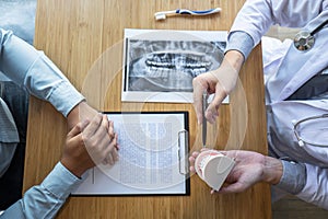 Professional Dentist showing  jaw and teeth the x-ray photograph and discussing during explaining the consultation treatment