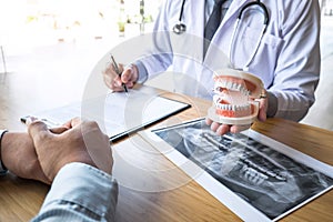 Professional Dentist showing  jaw and teeth the x-ray photograph and discussing during explaining the consultation treatment