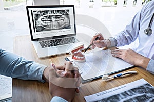 Professional Dentist showing  jaw and teeth the x-ray photograph and discussing during explaining the consultation treatment photo