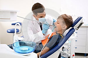 Professional dentist working with little boy