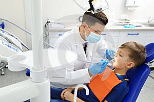 Professional dentist working with little boy