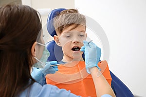 Professional dentist working with little boy