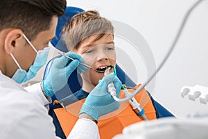 Professional dentist working with little boy