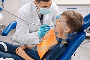 Professional dentist working with little boy